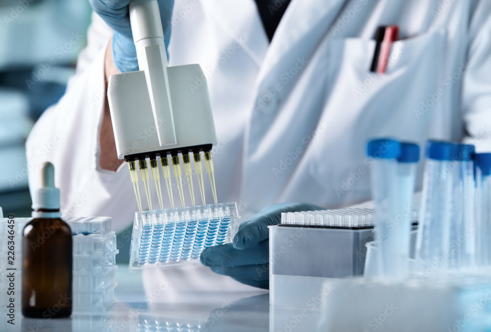 Scientist filling a tray with pipettes in a bright room