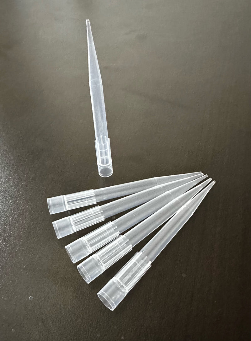 A collection of clear, disposable pipette tips laid out on a surface.